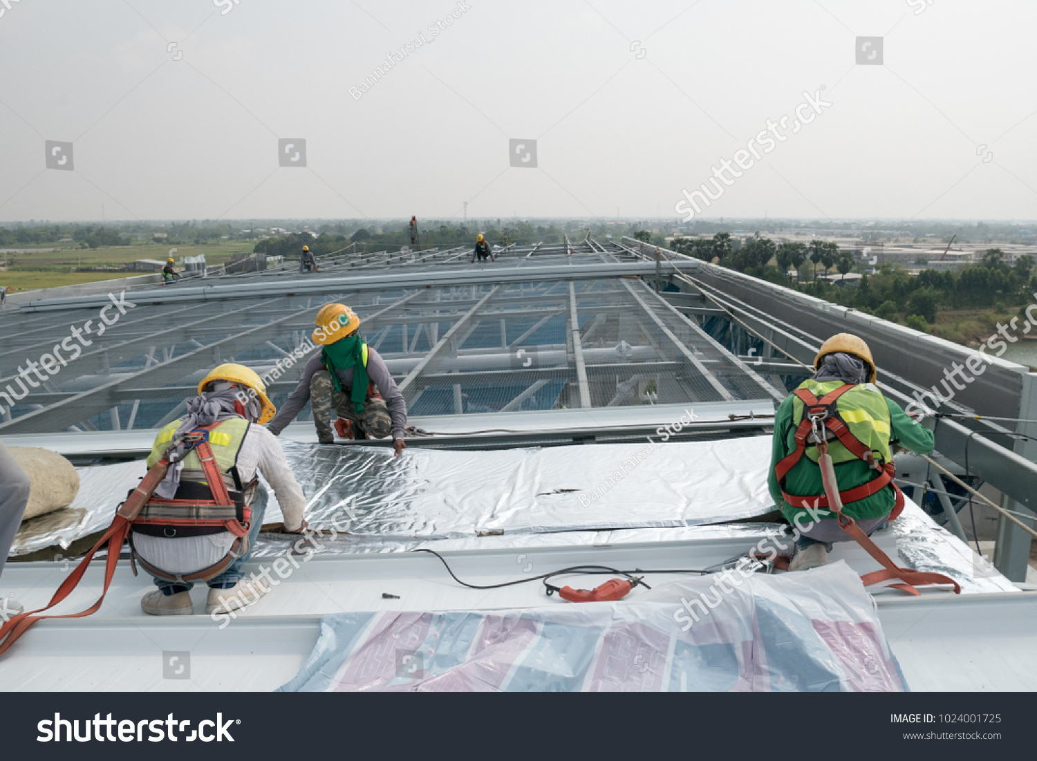 stock-photo-construction-worker-wearing-safety-harness-and-safety-line-working-on-a-metal-industry-roof-new-1024001725