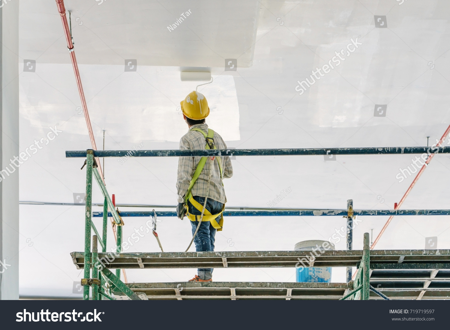 stock-photo-worker-man-painting-a-gypsum-plaster-ceiling-with-paint-roller-on-the-scaffold-719719597